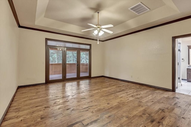 1008 Bavarian Dr, Edmond, OK 73034 - empty room featuring a raised ceiling, light wood-style flooring, french doors, ceiling fan, and ornamental molding