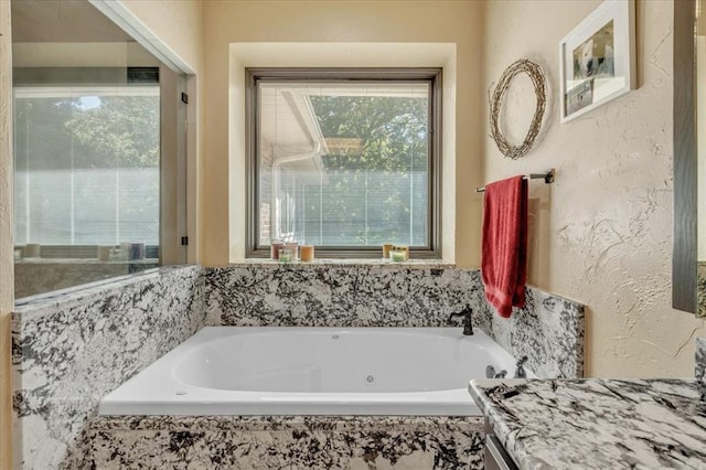 1008 Bavarian Dr, Edmond, OK 73034 - bathroom featuring a tub with jets, vanity, and a textured wall