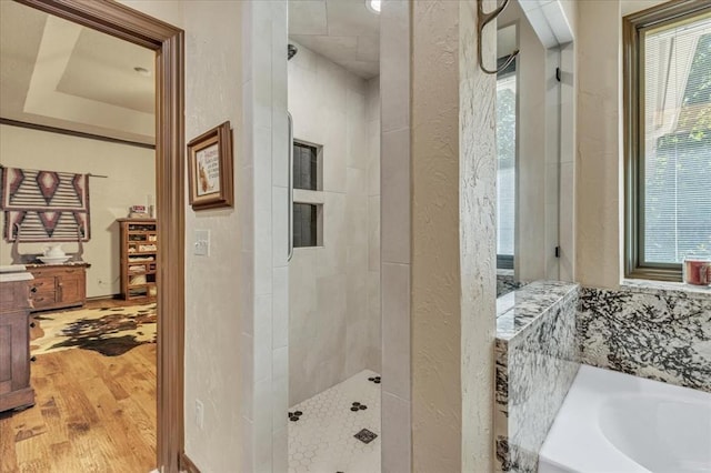 1008 Bavarian Dr, Edmond, OK 73034 - bathroom with a textured wall, a bath, wood finished floors, plenty of natural light, and a tile shower