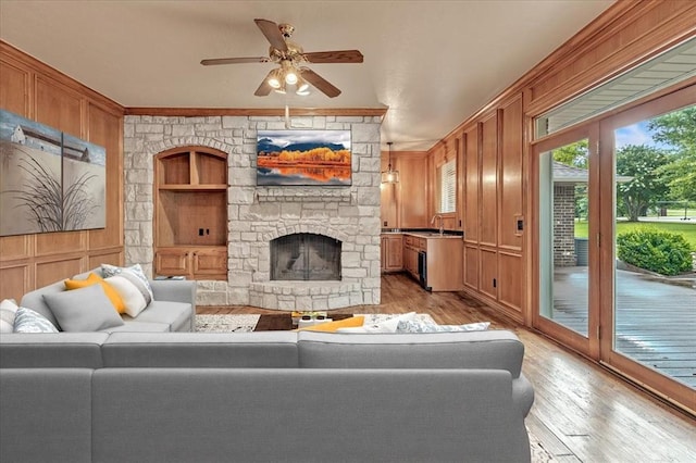 1008 Bavarian Dr, Edmond, OK 73034 - living area featuring light wood-style flooring, a ceiling fan, a fireplace, a decorative wall, and crown molding