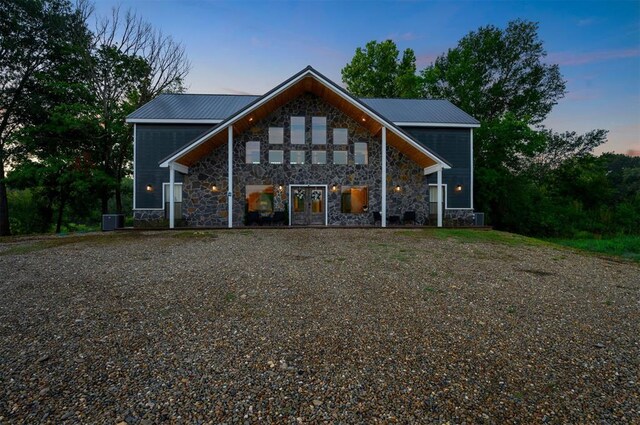 370 Stones River Ln, Broken Bow, OK 74728 - back of property at dusk featuring stone siding, metal roof, and cooling unit