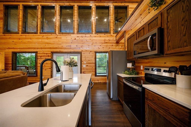 370 Stones River Ln, Broken Bow, OK 74728 - kitchen with appliances with stainless steel finishes, a sink, light countertops, wooden walls, and dark wood-style floors