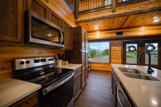 370 Stones River Ln, Broken Bow, OK 74728 - kitchen with stainless steel appliances, a sink, wooden walls, dark wood finished floors, and light countertops