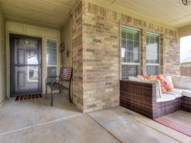 view of exterior entry featuring a porch and brick siding