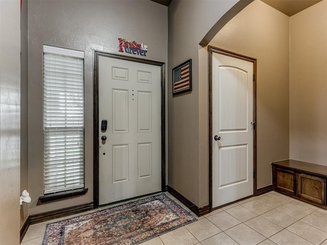 foyer entrance featuring light tile patterned floors, baseboards, and arched walkways