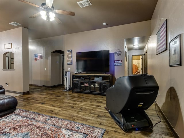 living area with arched walkways, a ceiling fan, visible vents, and wood finished floors