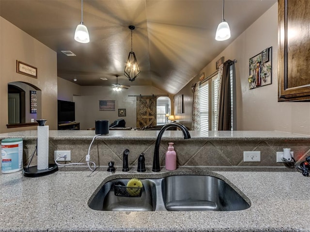 kitchen with visible vents, open floor plan, a sink, vaulted ceiling, and decorative light fixtures