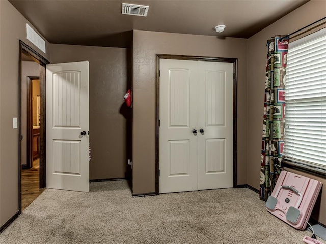 unfurnished bedroom with baseboards, light carpet, and visible vents
