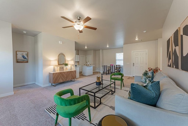 living area with a ceiling fan, baseboards, and light carpet
