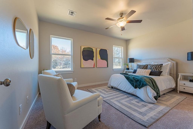 carpeted bedroom featuring visible vents, baseboards, ceiling fan, and multiple windows
