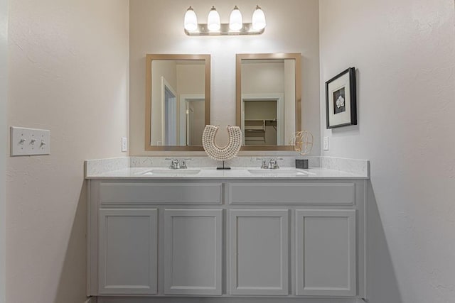 bathroom featuring a sink, a textured wall, and double vanity