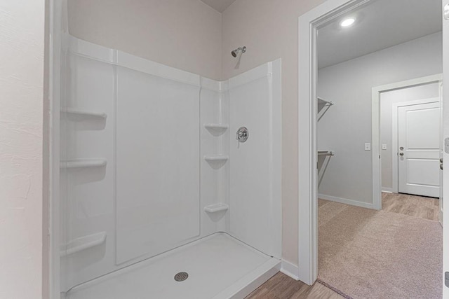 bathroom with baseboards, recessed lighting, wood finished floors, and a shower stall