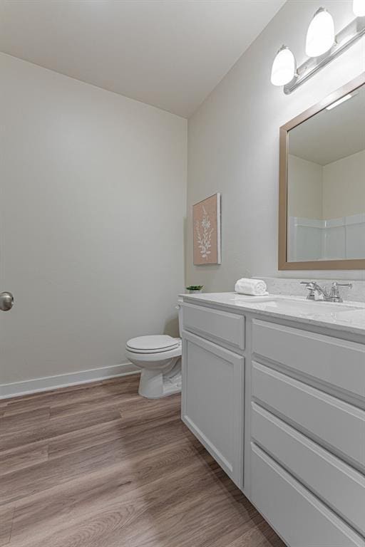bathroom with toilet, wood finished floors, and vanity