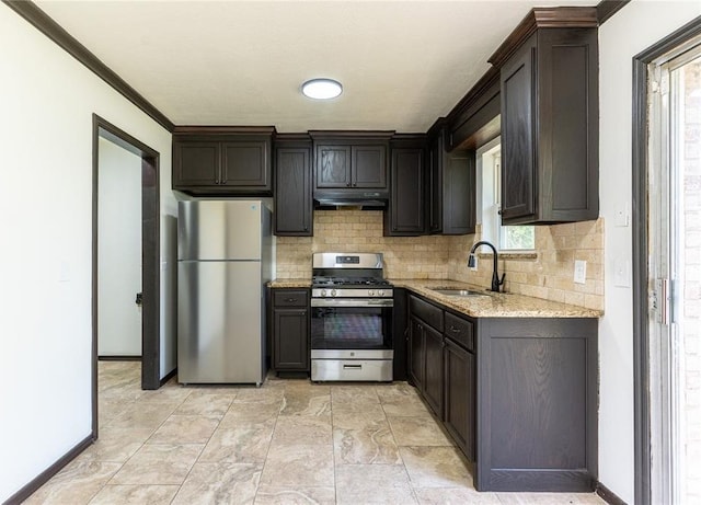kitchen featuring light stone countertops, appliances with stainless steel finishes, decorative backsplash, and a sink