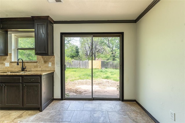 entryway with baseboards, a sink, visible vents, and ornamental molding