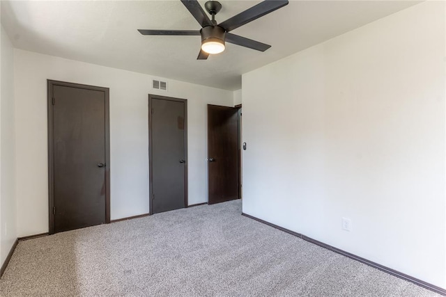unfurnished bedroom featuring visible vents, carpet floors, two closets, baseboards, and a ceiling fan