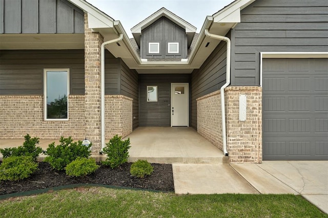 doorway to property featuring brick siding and an attached garage