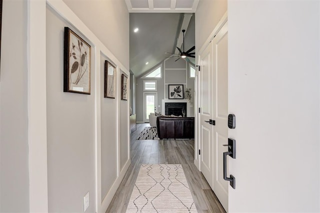 hallway featuring light wood finished floors, a towering ceiling, recessed lighting, and baseboards