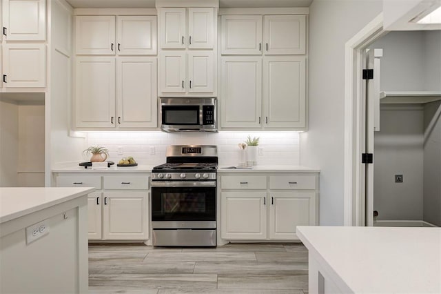 kitchen with appliances with stainless steel finishes, light countertops, white cabinetry, and tasteful backsplash