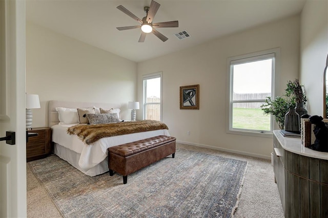 bedroom with multiple windows, light colored carpet, baseboards, lofted ceiling, and ceiling fan