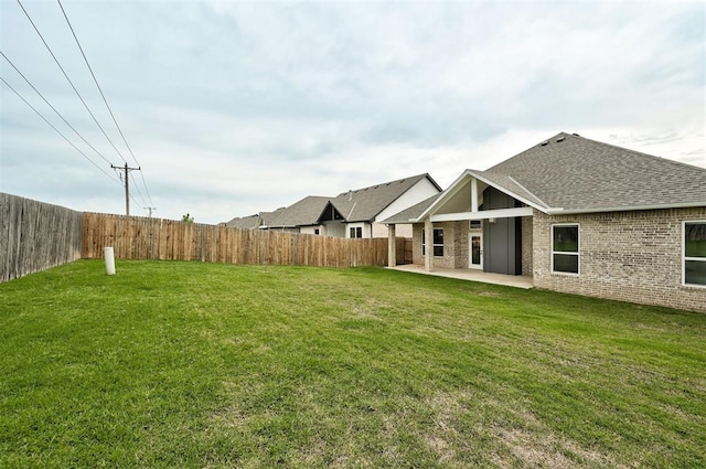 rear view of house with a patio, roof with shingles, and brick siding