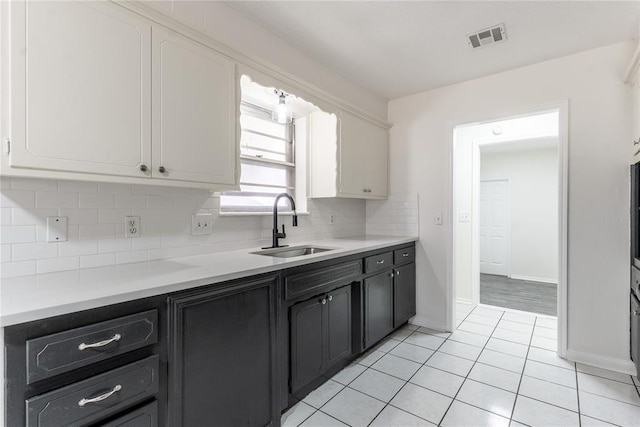 kitchen featuring a sink, light countertops, white cabinetry, decorative backsplash, and visible vents