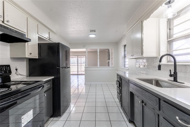 kitchen with light tile patterned flooring, a sink, light countertops, black / electric stove, and under cabinet range hood