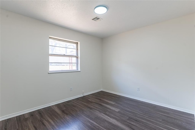 spare room with visible vents, dark wood finished floors, and baseboards