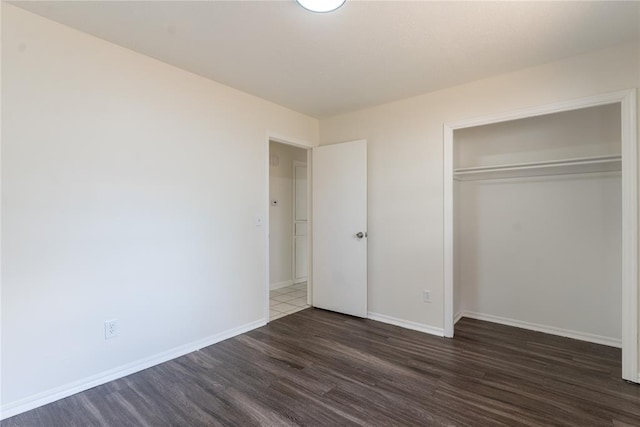 unfurnished bedroom with baseboards, wood finished floors, and a closet