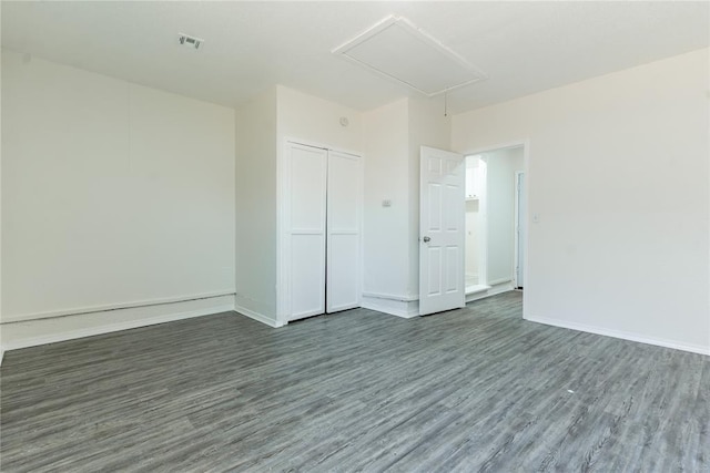 spare room featuring baseboards, attic access, dark wood finished floors, and visible vents