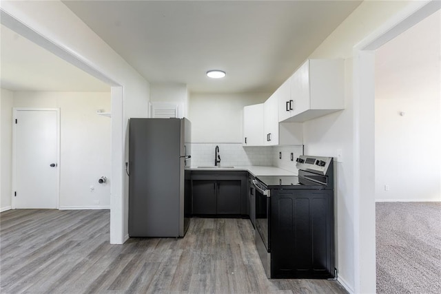 kitchen featuring a sink, electric range oven, freestanding refrigerator, white cabinetry, and backsplash