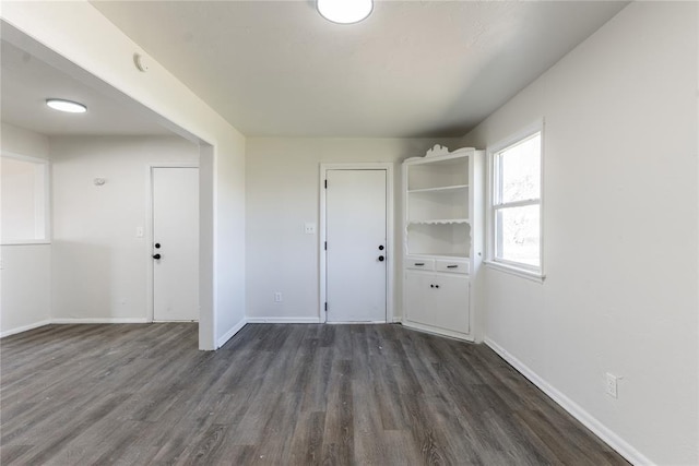 empty room with dark wood-style flooring and baseboards