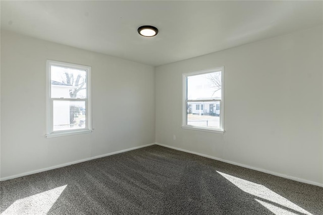 spare room with dark carpet and baseboards