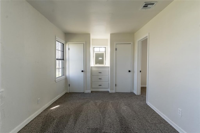unfurnished bedroom with visible vents, carpet, multiple closets, and baseboards