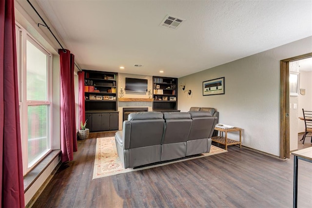 living room featuring a healthy amount of sunlight, baseboards, visible vents, and dark wood-type flooring