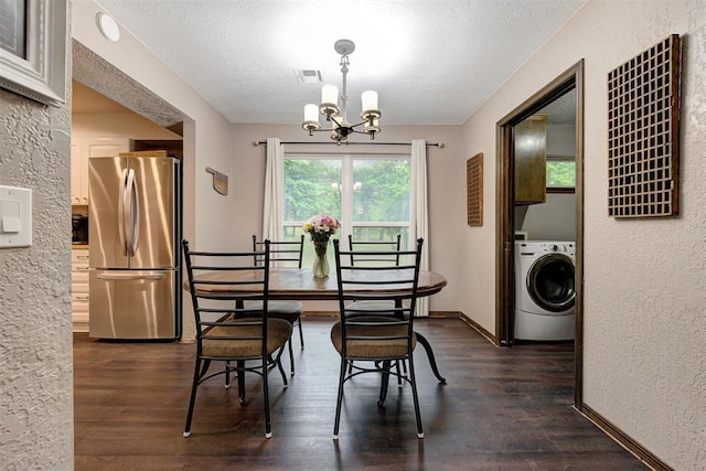 dining space featuring a textured ceiling, dark wood finished floors, washer / clothes dryer, and a notable chandelier