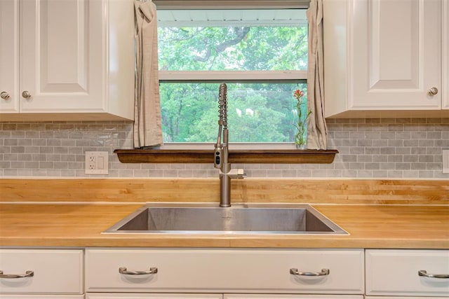 kitchen with a sink, white cabinets, and a wealth of natural light