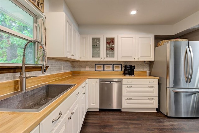 kitchen with a sink, glass insert cabinets, stainless steel appliances, and white cabinetry