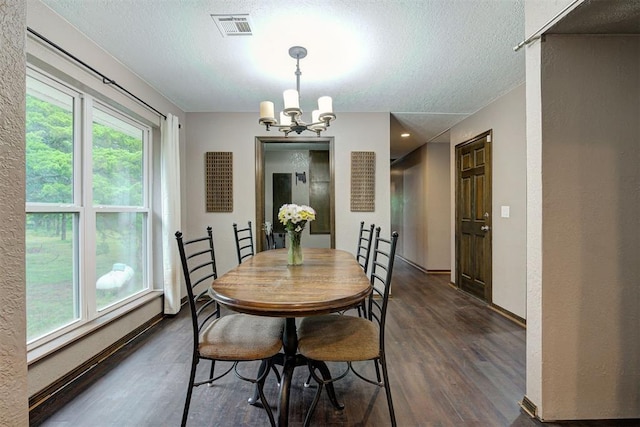 dining room with a textured ceiling, a notable chandelier, visible vents, and dark wood finished floors