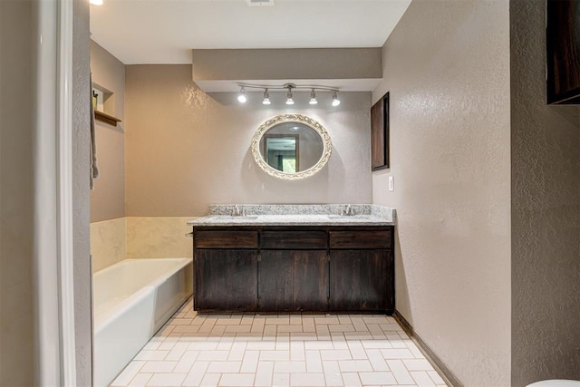 full bathroom featuring vanity, tile patterned flooring, a textured wall, track lighting, and a bath