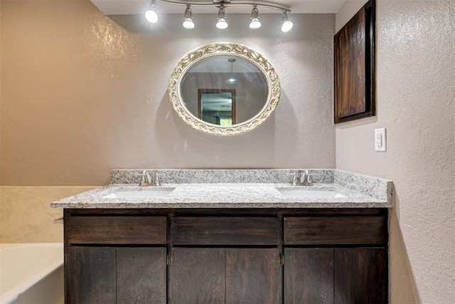bathroom with a sink, a textured wall, and rail lighting