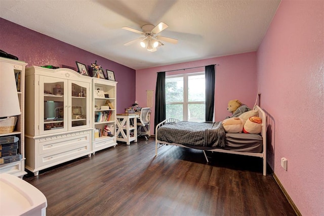 bedroom featuring a ceiling fan, a textured wall, a textured ceiling, and dark wood finished floors