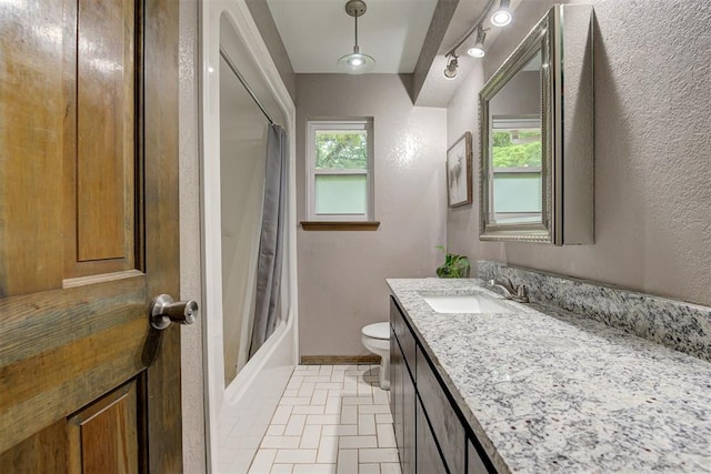full bath featuring vanity, a textured wall, toilet, baseboards, and shower / tub combo
