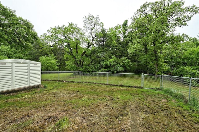 view of yard featuring a storage shed, fence, and an outbuilding