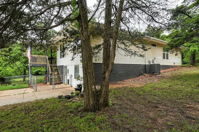 view of home's exterior with fence, a wooden deck, stairway, central AC unit, and a patio