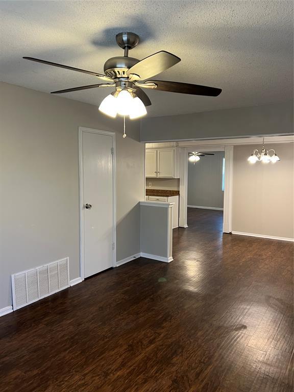 924 N Bradley Ave, Oklahoma City, OK 73127 - unfurnished living room with visible vents, baseboards, dark wood-type flooring, a textured ceiling, and a ceiling fan