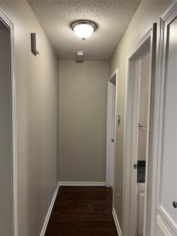 924 N Bradley Ave, Oklahoma City, OK 73127 - hall featuring baseboards, a textured ceiling, and dark wood-style floors