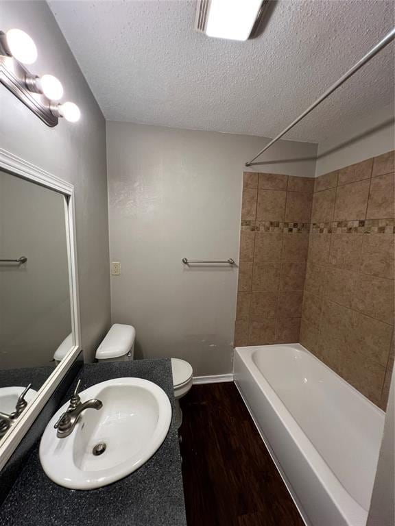 924 N Bradley Ave, Oklahoma City, OK 73127 - full bath featuring vanity, tub / shower combination, wood finished floors, toilet, and a textured ceiling