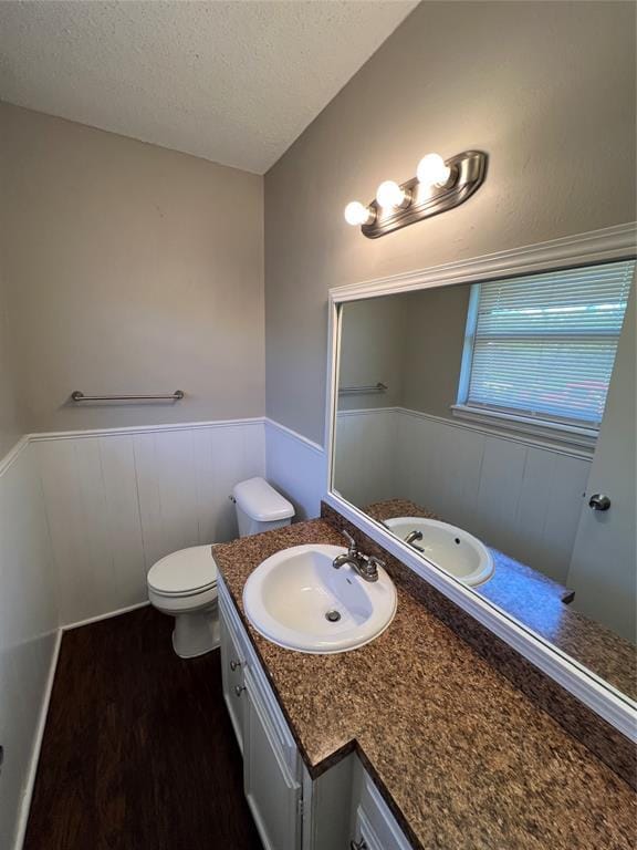 924 N Bradley Ave, Oklahoma City, OK 73127 - bathroom with vanity, wainscoting, wood finished floors, toilet, and a textured ceiling