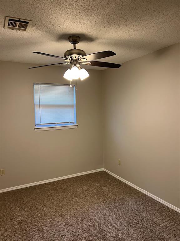924 N Bradley Ave, Oklahoma City, OK 73127 - unfurnished room with ceiling fan, a textured ceiling, dark colored carpet, baseboards, and visible vents
